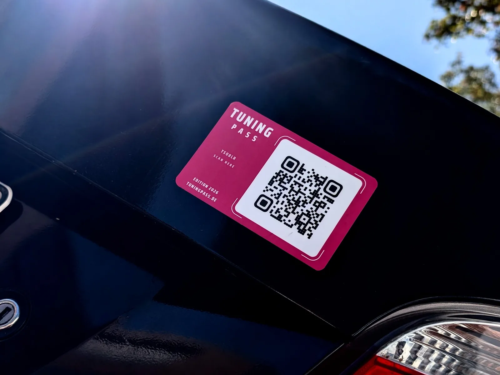 Der Tuningpass QR-Aufkleber an der Seitenscheibe eines roten Autos